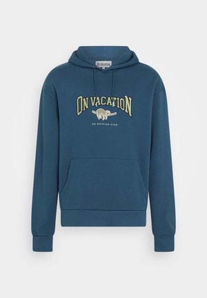 Blauer Kapuzenpullover mit Fronttasche, Schriftzug „ON VACATION“, Faultier-Grafik auf einem Ast und kleinerem Text „DO NOTHING CLUB“ darunter.