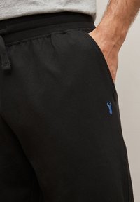 Sorte sweatpants lavet af bomuld med en elastisk talje og snørre. Har et lille broderet blåt hummer-logo på siden.