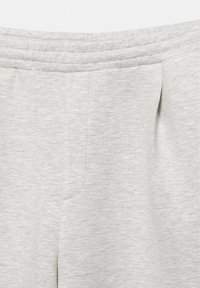 Close-up of light gray fabric pants showing elastic waistband and front seam detail.