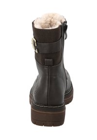 Brown ankle boot featuring a textured upper with plush lining, a side zipper, and a decorative strap with a metal buckle accent.