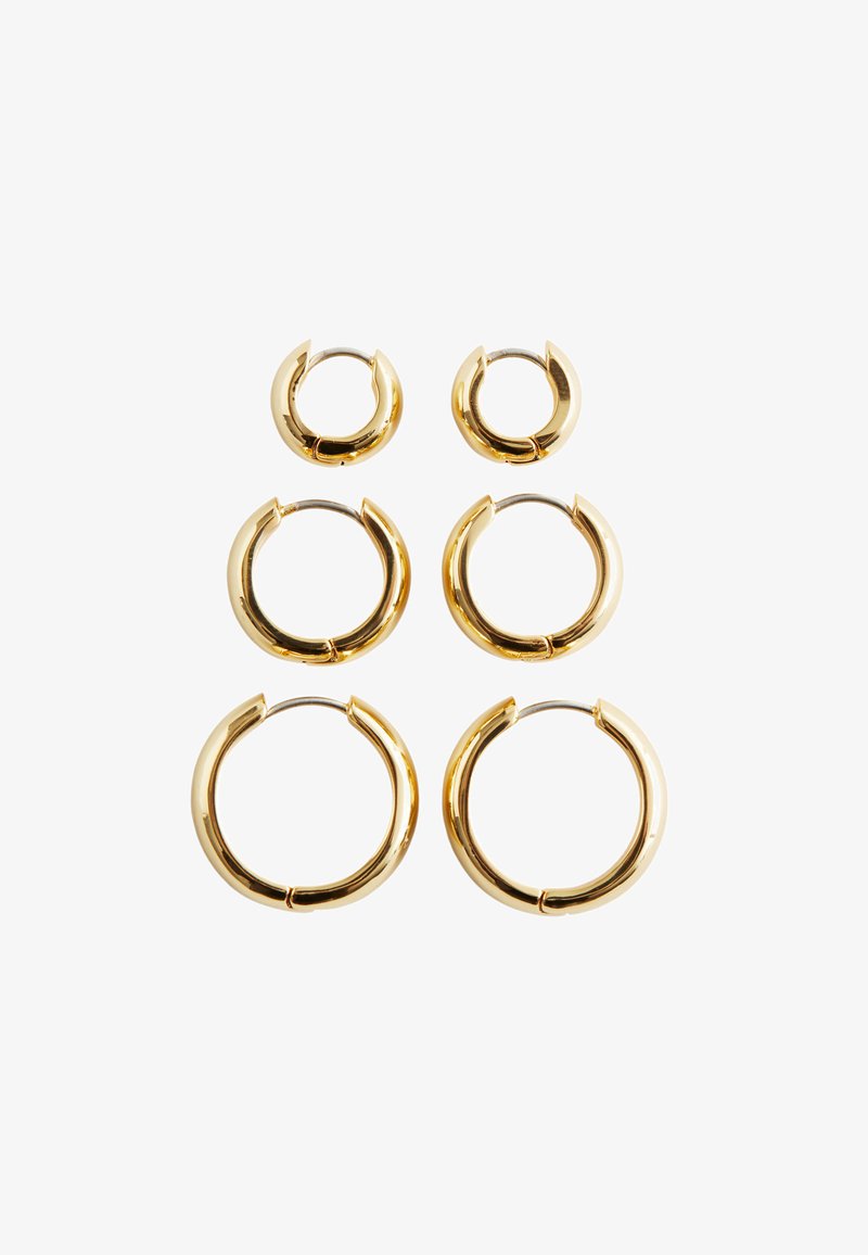 Ensemble de trois paires de boucles d'oreilles en métal doré, de tailles variées. Formes arrondies avec une finition lisse et réfléchissante et fermoirs ouverts.