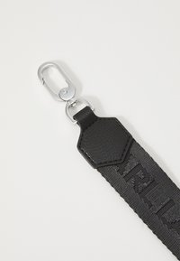 Black strap with textured fabric and leather accents. Features a silver hardware clip and embossed lettering on the strap surface.
