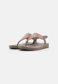 Ruske flip-flop s teksturiranim ružičastim zlatnim remenom, koji ima trokutasti dizajn i ravnu potplatu s blagim uzorkom za prianjanje.