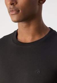 Sort kortærmet t-shirt lavet af blød bomuld. Har en ribbet rund halsudskæring og et diskret broderet logo på brystet.