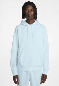 Felpa blu chiaro realizzata in morbido tessuto con tasca a marsupio, presenta un piccolo logo bianco Nike sul petto e polsini a coste.