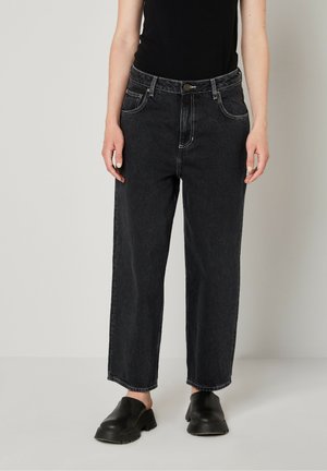 Zwarte denim wijde jeans met contrasterende stiksels, vijf zakken en een knoopsluiting, gecombineerd met zwarte instapschoenen.