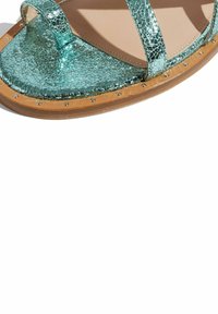 Metaliczne turkusowe sandały z popękaną teksturą, dwoma paskami i drewnianą podeszwą, ozdobione małymi srebrnymi ćwiekami wzdłuż krawędzi.