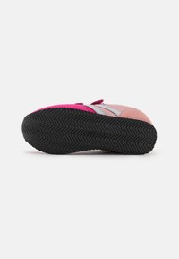 Baskets avec un dessus en suede rose et gris, une sangle Velcro et une semelle en caoutchouc noir avec un motif en chevron.