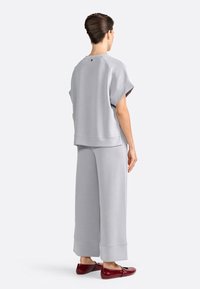 Lysegrå loungewear-sæt med en afslappet pasform, kortærmet top og brede bukser med en glat overflade, detaljeret syninger og sænket kant.
