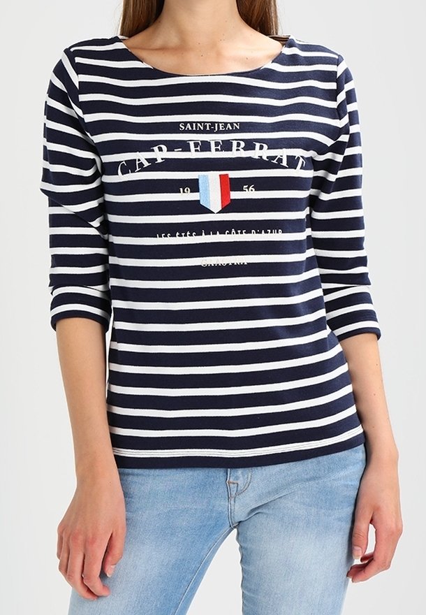 Marinblå och vit randig långärmad tröja med båthals, prydd med en logotyp och sköld i röd, vit och blå framtill.