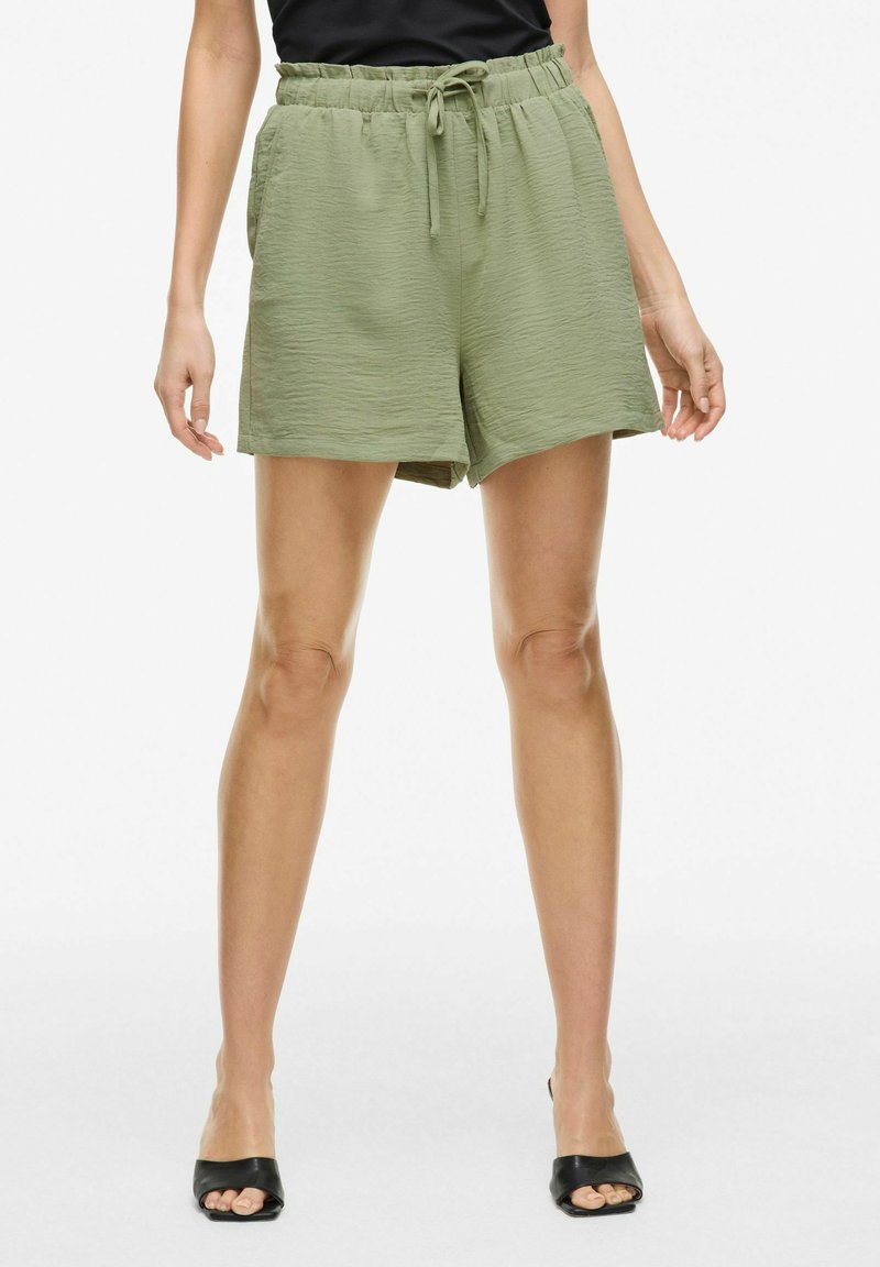 Shorts verts clairs en tissu texturé, avec une taille élastique et un détail de cordon de serrage. Comprend des poches latérales et un design ample.