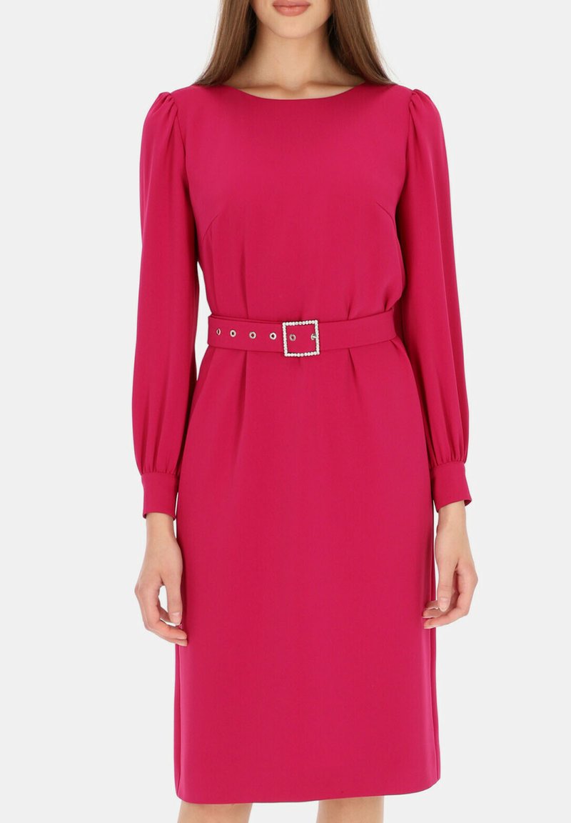 Fuksjowa sukienka z długimi rękawami, okrągłym dekoltem i paskiem w talii z prostokątną srebrną klamrą i dekoracyjnymi ćwiekami. Gładka tekstura.