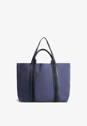 Grand sac cabas rectangulaire bleu marine avec poignées noires et bandes verticales affichant le texte "Ted Baker London" sur chaque bande.