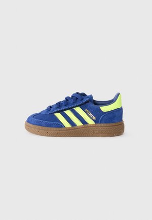 Baskets Adidas bleues avec des bandes jaunes, semelle en gomme et languette de talon jaune néon, vues côté intérieur sur fond clair.