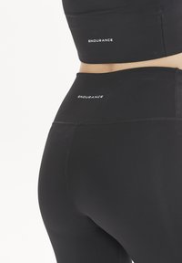 Svart träningsset som inkluderar en åtsittande sport-bh och högmidjade leggings, tillverkade av elastiskt material med vit "ENDURANCE"-logotyp.