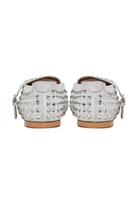 Scarpe in suede grigio con punta arrotondata, decorate con borchie metalliche e una cintura laterale con fibbia, dotate di una suola piatta in gomma color cuoio.