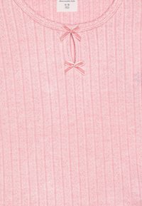 Haut côtelé rose avec un col rond. Deux petits nœuds rose clair accentuent la zone du cou. L'étiquette indique la taille 9/10 et la marque est Abercrombie Kids.