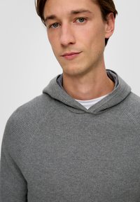 Gray ribbed hoodie with a front pocket and drawstring at the neck. Soft texture and casual, fitted design. Background is white.