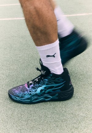 Schwarzer Sportschuh mit aufwändigen türkisfarbenen und lila Flammenmustern. Hergestellt aus strapazierfähigem Material, mit Schnürsenkeln und Logodetails. Getragen mit weißen Socken.