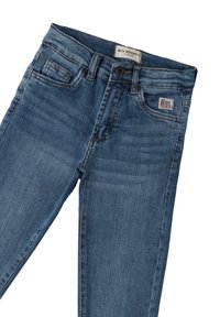 Vaqueros de mezclilla en un lavado azul medio con corte recto, que cuentan con un bolsillo frontal y una etiqueta de marca en el bolsillo trasero.