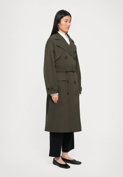 Olivgrüner Trenchcoat mit doppelter Knopfleiste, großen Revers und einem Taillengürtel. Verfügt über zwei große Fronttaschen und lange Ärmel.