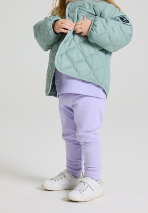 Padded mint green jacket with diamond quilting, layered over a lavender sweatshirt and matching sweatpants, completed with white sneakers.