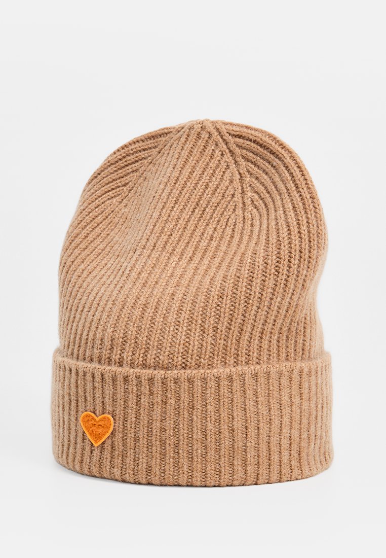 Jasnobrązowy, prążkowany czapka beanie z podwiniętym mankietem i małą pomarańczową łatką w kształcie serca po lewej stronie.