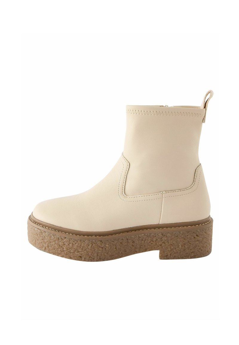 Cremfarbene Leder-Ankle Boots mit einer strukturierten Kork-Plattformsohle, elastischen Seitenpaneelen und einer hinteren Zuglasche für einfaches An- und Ausziehen.