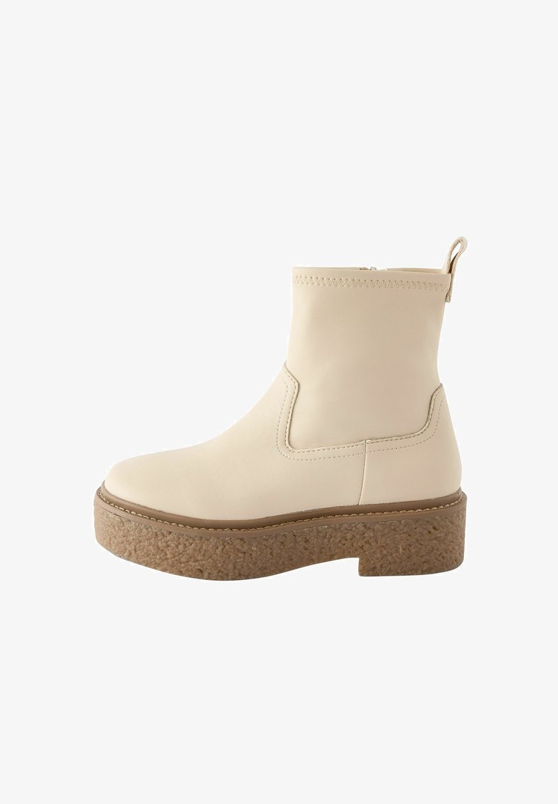 Kremowe skórzane botki za kostkę z teksturowaną korkową podeszwą, elastycznymi bocznymi panelami oraz tylną pętlą ułatwiającą zakładanie.