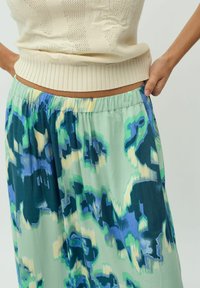 Gonna lunga con un motivo astratto verde, blu e crema. Tessuto leggero con una vita elastica per il massimo comfort.