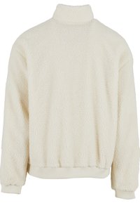 Fleece pullover in cream with a high collar, elastic cuffs, and waistband. Textured surface with a soft, cozy appearance.