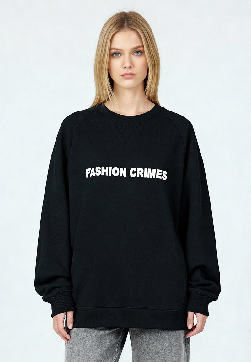 Sweat-shirt noir avec le texte "FASHION CRIMES" en blanc, doté d'un col rond, de manches raglan longues et de poignets et ourlet côtelés.