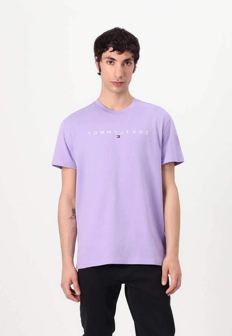 Lavendel T-Shirt mit kurzen Ärmeln aus Baumwolle, ausgestattet mit dem "TOMMY JEANS"-Logo in Weiß auf der Brust und einem runden Ausschnitt.