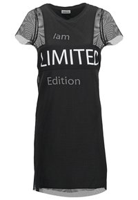 Svart nät t-shirtklänning med kontrasterande vit text som säger "Jag är en Begränsad Upplaga." Korta ärmar och avslappnad passform.