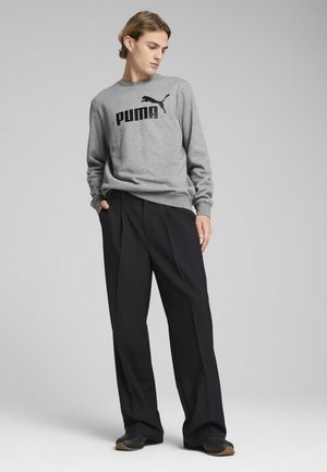 Grå sweatshirt med sort Puma-logo, parret med sorte vidde bukser. Outfitten har ribbede manchetter og et afslappet design.