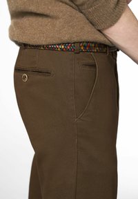 Pantalons marron texturé avec poches latérales, rehaussés par une ceinture tissée colorée aux motifs entrelacés rouge, bleu et jaune.