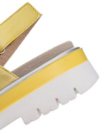 Yellow leather sandal with beige suede footbed and thick white rubber sole with deep treads, shown in close-up on white background.