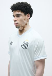 Balts futbola krekls ar gaiši zili akcentiem. Iekļauj v-veida kakla izgriezumu, S.F.C. logo ar svītrām un īsām piedurknēm. Gluda tekstūra.