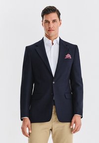 Granatowa marynarka z teksturowanej tkaniny, z dwoma przednimi kieszeniami, zapinana na jeden guzik, z wzorzystą poszetką w kieszeni na wysokości piersi.