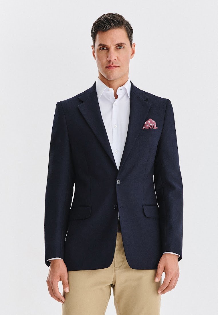 Granatowa marynarka z teksturowanej tkaniny, z dwoma przednimi kieszeniami, zapinana na jeden guzik, z wzorzystą poszetką w kieszeni na wysokości piersi.