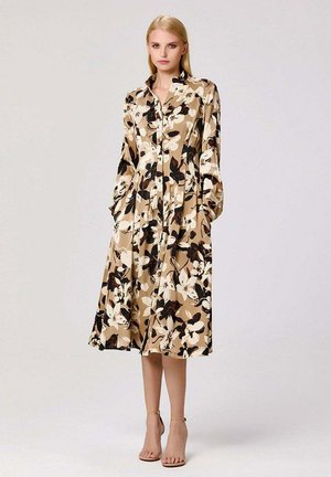 Robe midi florale beige, avec des motifs floraux noirs et blancs, manches longues, boutonnage à l'avant et poches latérales. Tissu texturé.