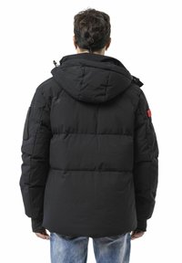 Schwarze Steppjacke mit Kapuze, mit einem gesteppte Design und einem roten Logo-Patch am Ärmel. Weiche Textur und lässige Passform.