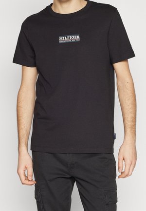 Schwarzes T-Shirt mit kurzen Ärmeln aus Baumwolle. Verfügt über ein kleines weiß-blaues "HILFIGER"-Logo auf der Brust. Gerader Saum und Rundhalsausschnitt.