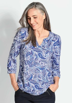 Blaue und weiße bedruckte Bluse mit V-Ausschnitt, drei Viertel langen Ärmeln und lockerer Passform, die ein Paisleymuster und eine weiche Stofftextur aufweist.