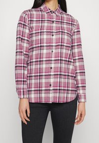 Randig skjorta i rosa, vitt och svart, med krage, långa ärmar och rak skärning. Tillverkad av mjukt tyg med borstad yta.