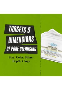 Kiehl's Rare Earth Deep Pore Cleansing Masque i en vit burk med blå text, bredvid kraftig svart typografi på en lysgrön bakgrund.