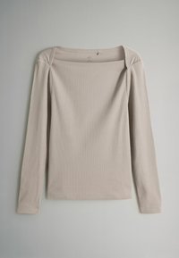 Kerge beež pikaaene särk avara paadi kaelusega, ribakujuline tekstuur ja sirge lõikega alläär. Omab õmblusi õlgadel.