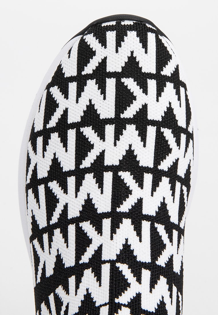 Punta de zapatilla de punto en blanco y negro con un patrón geométrico repetitivo de las letras "MK" en orientaciones alternas.