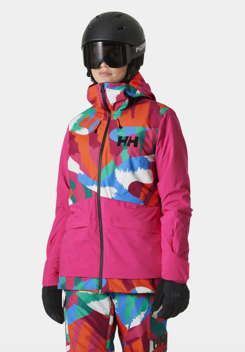 Kleurige skijas met een mix van roze, oranje, groene en blauwe patronen, gemaakt van duurzaam materiaal, met een hoge kraag en ritssluiting.