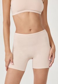 Shorts taille haute nus et sans couture, fabriqués à partir d'un tissu doux et extensible, avec une texture lisse et une ceinture élastique pour le confort.